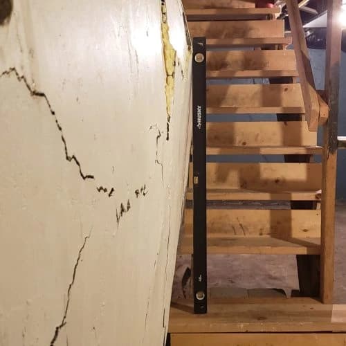 Bowing basement wall with cracks and level tool